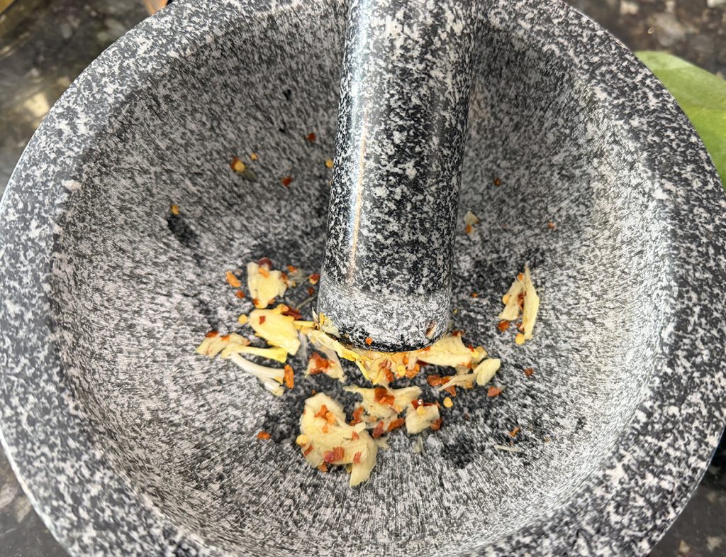 mortar and pestle grinding garlic and chilis